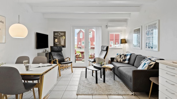 A modern living room with a dining area, a TV, and a large window with a view of a red building. - 3 bedroom gorgeous home in Hadsund (Hadsund)