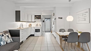 A modern kitchen with white cabinets, a built-in oven, and a dining area with a wooden table and chairs. - 3 bedroom gorgeous home in Hadsund (Hadsund)