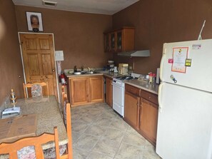Kitchen features an oven, stove, and refrigerator, along with various kitchen items on the countertop.