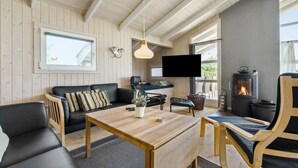 A cozy living room with a wooden ceiling, a flat-screen TV, a fireplace, and a comfortable seating area. - Stunning home in Ringkøbing with sauna (Ringkøbing)