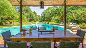 A covered outdoor area with a pool, wicker furniture, and a pergola. - Amazing home in Capdepera (Capdepera)