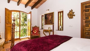 A bedroom with a large bed, a wooden chair, a table, and a painting on the wall. - Amazing home in Capdepera (Capdepera)