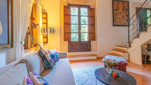 A living room with a sofa, a coffee table, a staircase, and a large window. - Amazing home in Capdepera (Capdepera)