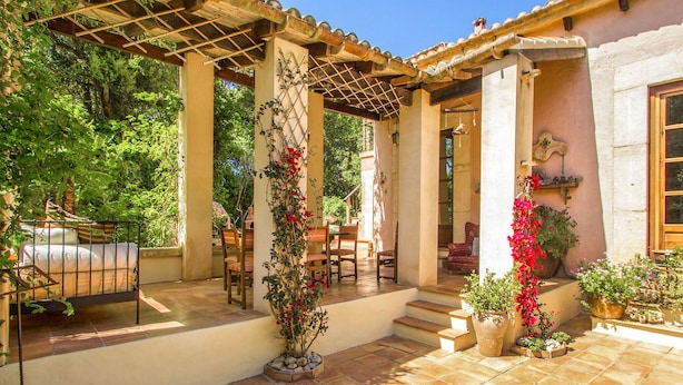 A covered patio with outdoor seating, a pergola, and potted plants. - Amazing home in Capdepera (Capdepera)