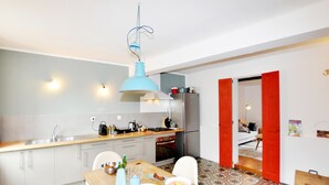 A modern kitchen with a blue pendant light, a stainless steel refrigerator, and a dining area with a patterned floor. - 3 bedroom pet friendly home in Castelreng (Castelreng)