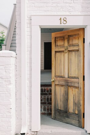 A white brick building with a wooden door labeled '18' and a visible brick fireplace. - Downtown - Near Historic Cigar Factory w/ Parking (Charleston)
