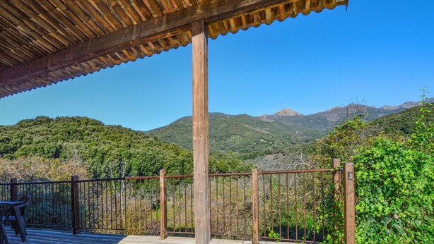 A wooden deck with a metal railing overlooking a mountainous landscape.