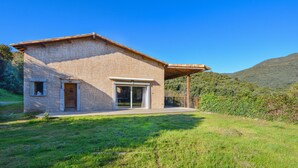 A single-story house with a stone facade, a large sliding glass door, and a covered porch.