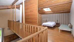 A wooden-floored bedroom with a bed, bedside table, and a skylight.