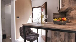 Una cocina moderna con una mesa de madera, dos copas de vino, una botella de vino y una cesta de fruta.