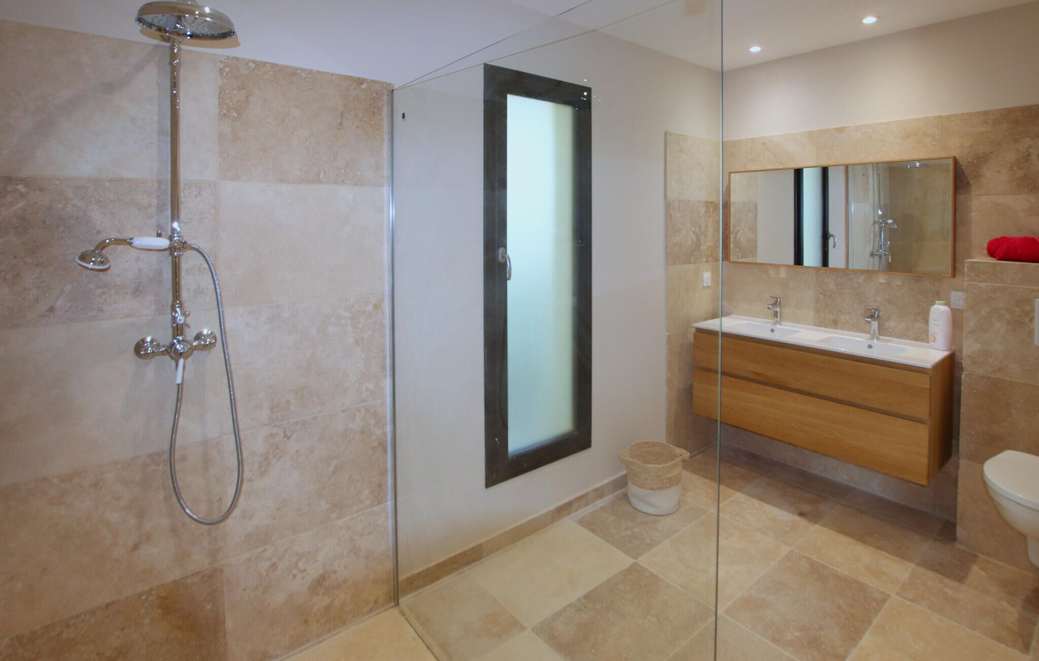 Une salle de bain moderne avec une douche à parois de verre, un grand miroir et un meuble-lavabo en bois doté de deux vasques.
