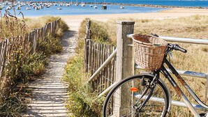 Ein hölzerner Weg führt zu einem Strand mit Booten im Wasser.