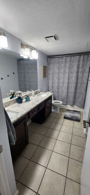 A bathroom with a marble sink, a toilet, and a shower curtain.