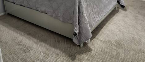 Un dormitorio con cama, ventilador de techo y piso alfombrado.