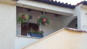En balkon med hængende blomsterkrukker og en potteplante.