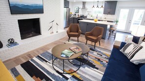 Una sala moderna con chimenea, un sofá, dos sillones y una mesita de centro.