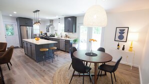 Una cocina moderna con una isla central, taburetes de bar y una mesa de comedor con sillas.