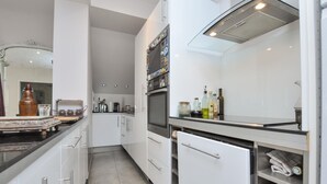 A modern kitchen with white cabinets, a built-in oven, a dishwasher, and various kitchen appliances. - Amazing apartment in Saint-Jeannet with WiFi (Saint-Jeannet)