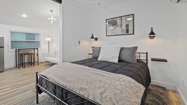 Un dormitorio moderno con cama, ventilador de techo y zona de escritorio.
