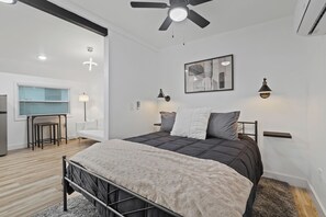 Un dormitorio moderno con cama, ventilador de techo y zona de escritorio.