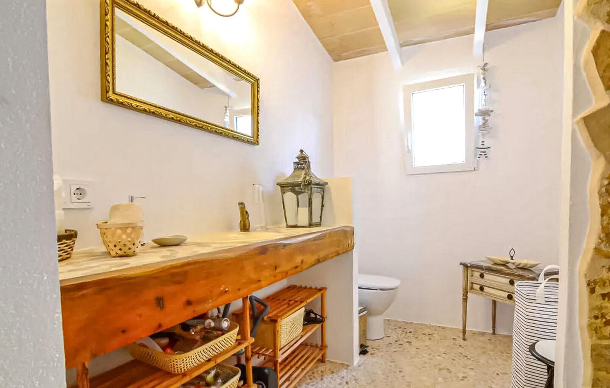 Ein Badezimmer mit einem Holzbadezimmer-Schrank, einem Spiegel, einer Laterne und einem kleinen Tisch mit einem Stuhl.