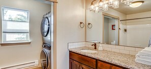 Une salle de bain équipée d’un lave-linge, d’un lavabo avec un meuble-vasque et d’un grand miroir.
