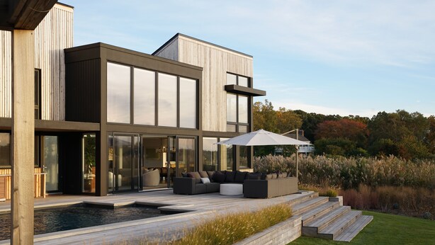 Une maison moderne dotée d’une piscine, d’un espace salon extérieur et d’un jardin bien entretenu.