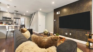 Una sala de estar moderna con un sofá, una mesa de centro y un televisor de pantalla plana montado en la pared.