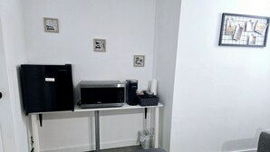 A kitchenette with a microwave, coffee maker, and a small refrigerator. There are two wall decorations and a trash bin below the counter. - COZY 1Br Basement Suite Perfect for Couple!Free Sparkling Wine! Private Parking. (Burnaby)