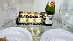A table set for two with a bottle of Martini & Rossi sparkling wine, two glasses, and a decorative centerpiece. - COZY 1Br Basement Suite Perfect for Couple!Free Sparkling Wine! Private Parking. (Burnaby)