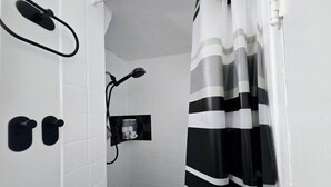 A small, white tiled bathroom with a shower curtain, a towel rack, and a wall-mounted towel dispenser. - COZY 1Br Basement Suite Perfect for Couple!Free Sparkling Wine! Private Parking. (Burnaby)