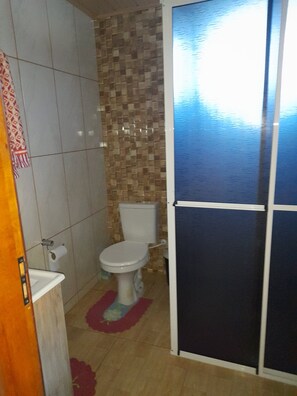 A small bathroom with a toilet, a sink, and a shower area.