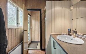 Bathroom features a large window, white sink, and mirror, with a door leading to another room.