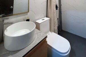 A bathroom with a white sink, toilet, and shower area.