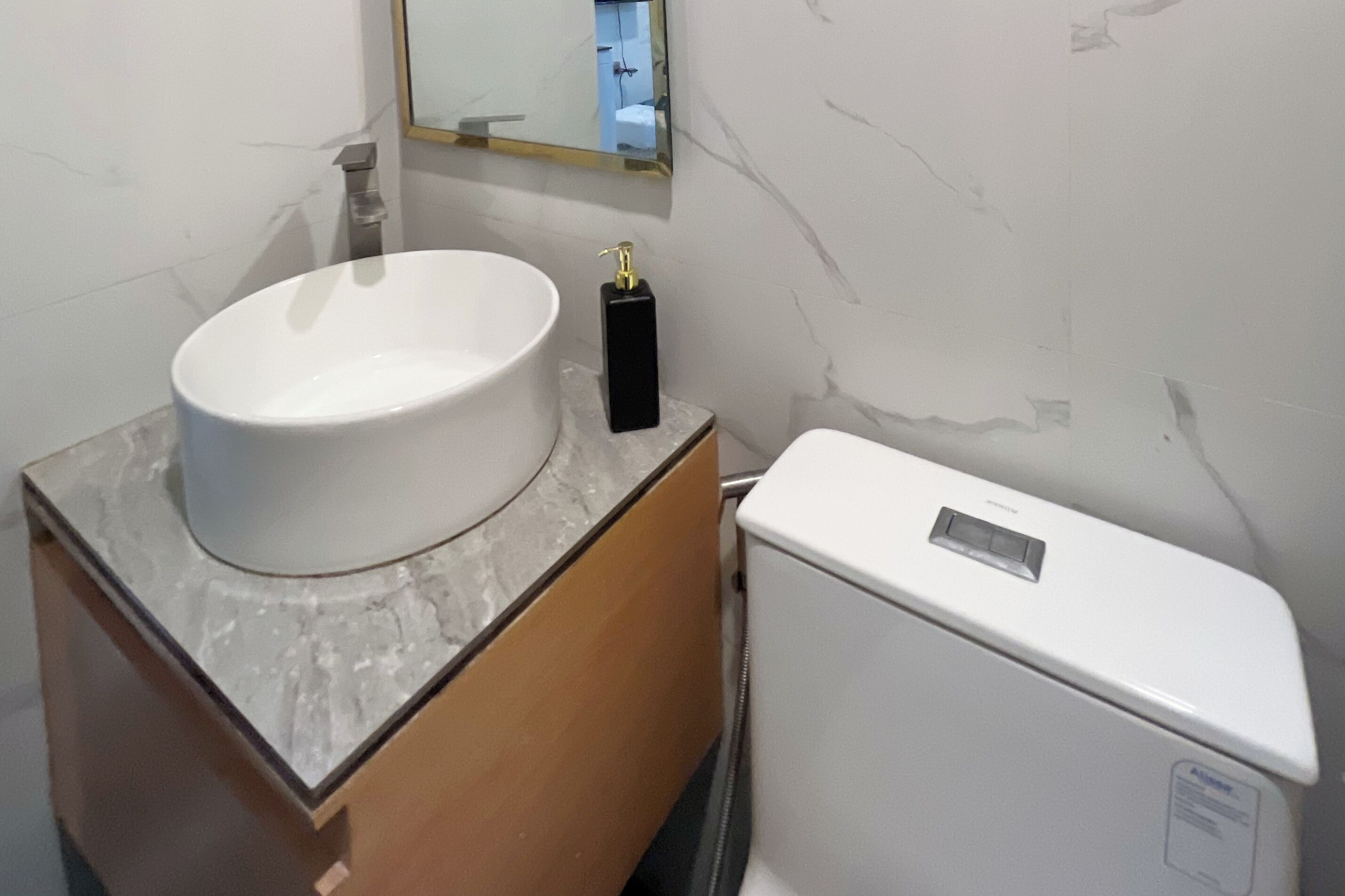 A bathroom with a white sink, a black soap dispenser, and a white toilet.