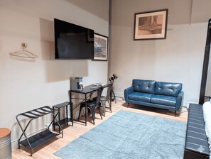 Un salon moderne avec un canapé en cuir bleu, une machine à café, un téléviseur et un tableau encadré accroché au mur.