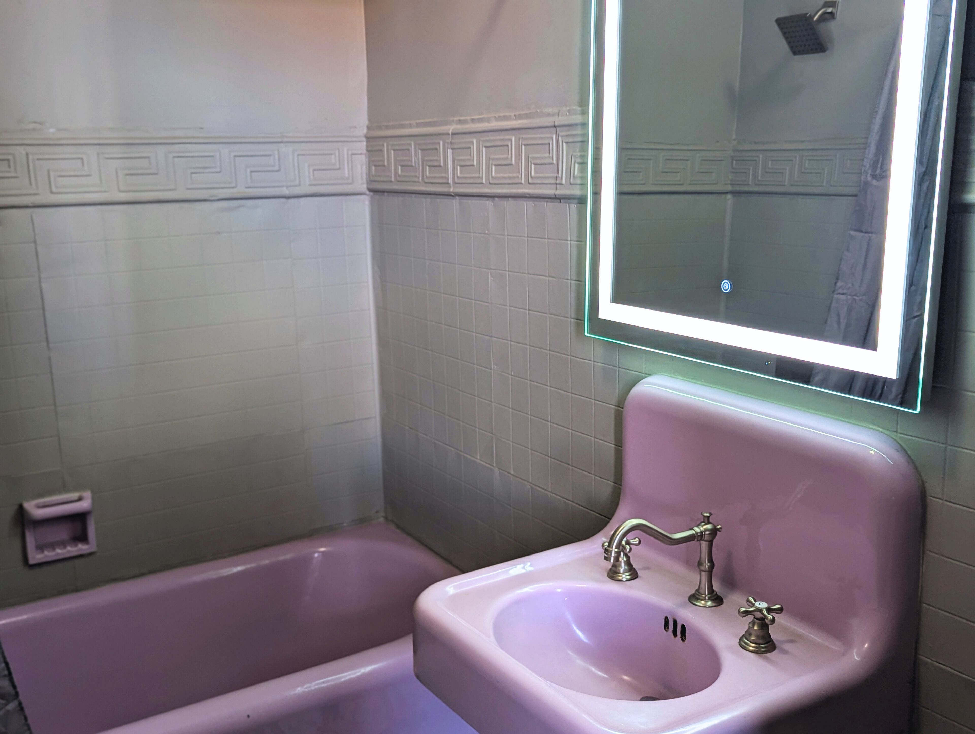 A bathroom with a pink sink, a mirror, and a bathtub.