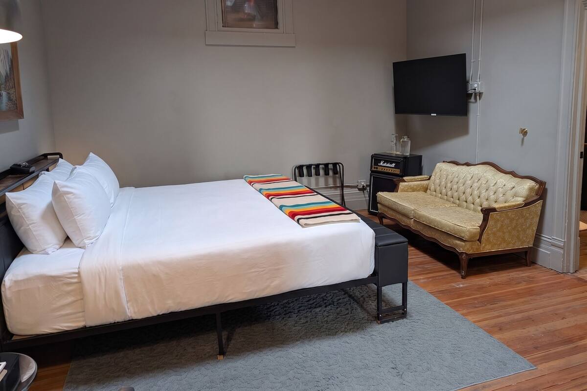 Un dormitorio con cama, sofá, televisor y una mesita.
