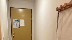 A hallway with a wooden floor, a door with a notice, a radiator, and a basket.
