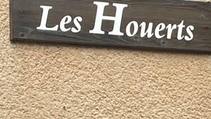 A wooden sign with the text "Les Houerts" on a textured beige background.