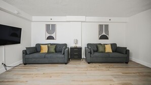 Una sala de estar moderna con dos sofás grises, un mueble de entretenimiento negro y un televisor de pantalla plana montado en la pared.