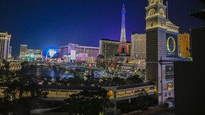 Vista nocturna del hotel Bellagio, con una réplica de la Torre Eiffel iluminada al fondo.