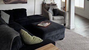 A modern living room with a sectional sofa, a coffee table, and a dining area with a chair and table. - Spacious 3-bedroom apartment in beautiful downtown Ketchikan  (Ketchikan)
