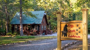 A wooden sign with a dog silhouette and the words "Cozy Creek Cubbhouse" indicating a pet-friendly lodging area.