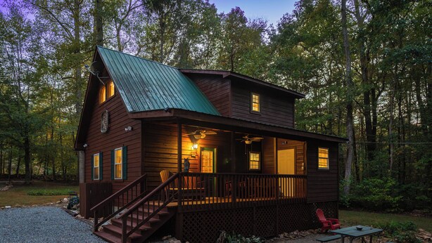 A wooden cabin with a porch, a staircase, and a picnic table.
