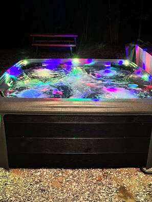 Ein Whirlpool mit farbigen Lichtern, umgeben von Kies.