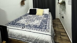 A bedroom with a bed, a desk, an air conditioner, a wall-mounted TV, and a curtain. - Villa between sea and mountain with beautiful places, live the adventure and romance. (Monte Rojo)