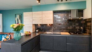 Une cuisine moderne avec des plans de travail sombres, des meubles de couleur bois clair et un pare-feu noir.
