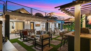A modern outdoor living space with a pool, seating areas, and a covered barbecue area.