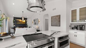 A modern kitchen with a large island, stainless steel appliances, and a dining area with a sofa and a fireplace.